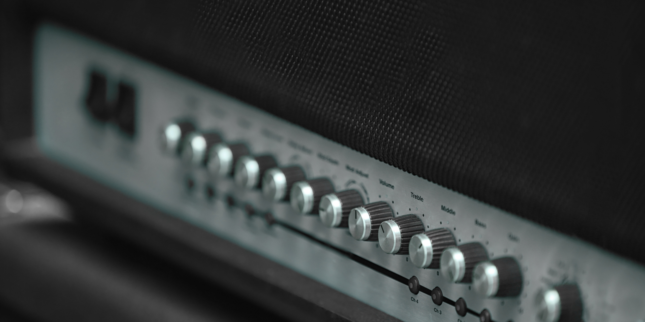 Close-up of a guitar amplifier with control knobs on a dark background