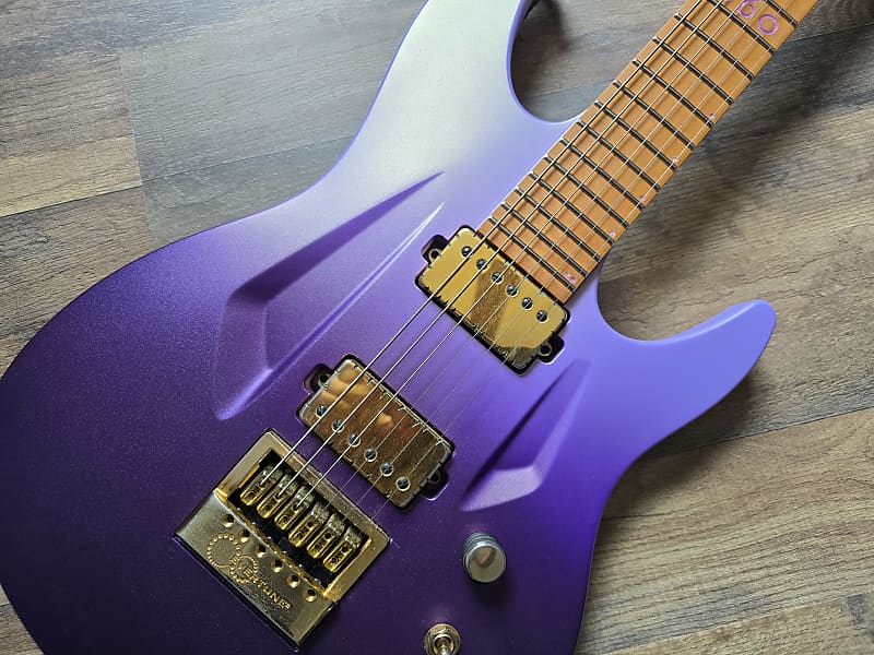 Purple electric guitar with gold hardware on a wooden surface
