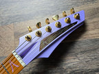 Close-up of a guitar headstock with gold tuning pegs and 'Aristides' branding