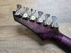 Pink and black guitar headstock with tuning pegs on a wooden surface