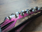 Close-up of a guitar headstock with tuning pegs on a wooden surface