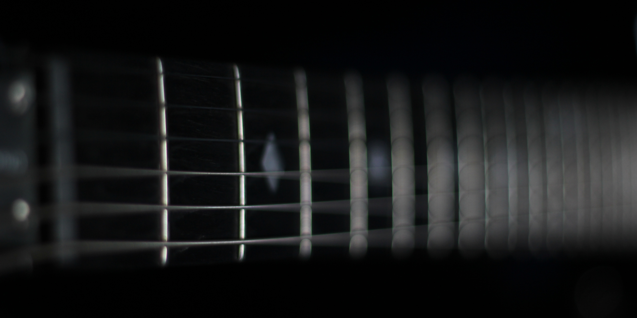 Close-up of a guitar neck with frets on a dark background