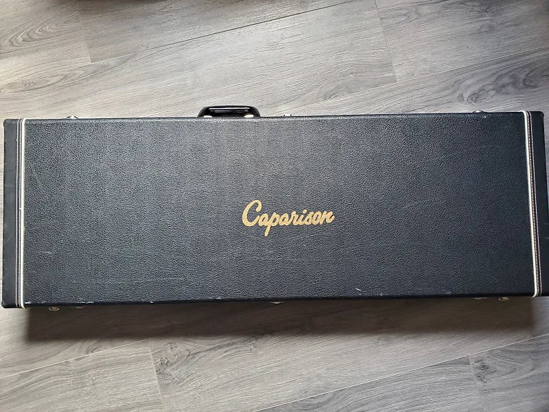 Guitar case with 'Caparison' branding on a wooden floor