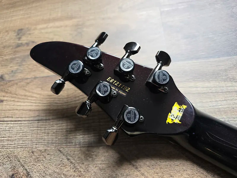 Guitar headstock with tuning pegs on a wooden surface