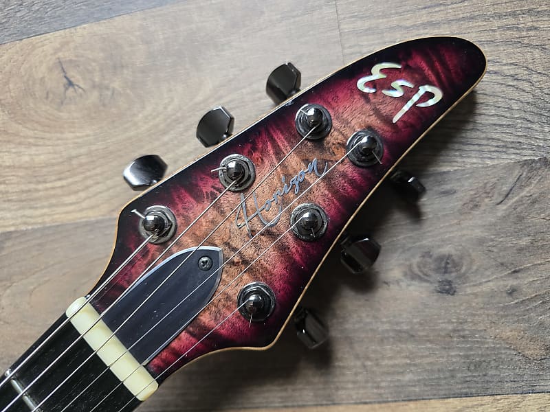 Pink and black guitar headstock with 'ESP Horizon' branding on a wooden surface