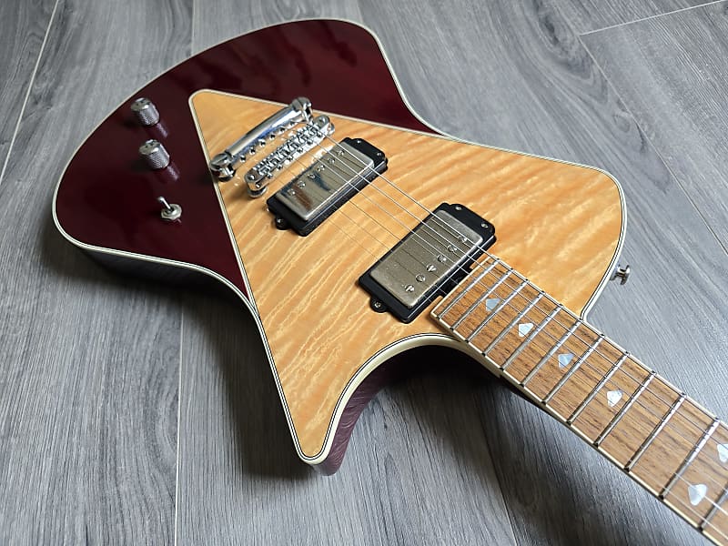 Electric guitar with a maroon finish on a wooden floor