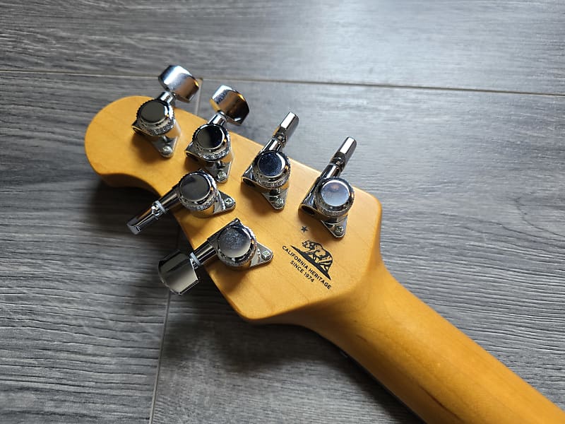 Guitar headstock with tuning pegs on a wooden surface