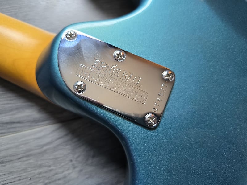 Close-up of an Ernie Ball Music Man guitar on a wooden surface