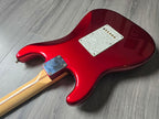 Red electric guitar with a beige neck on a gray wooden surface