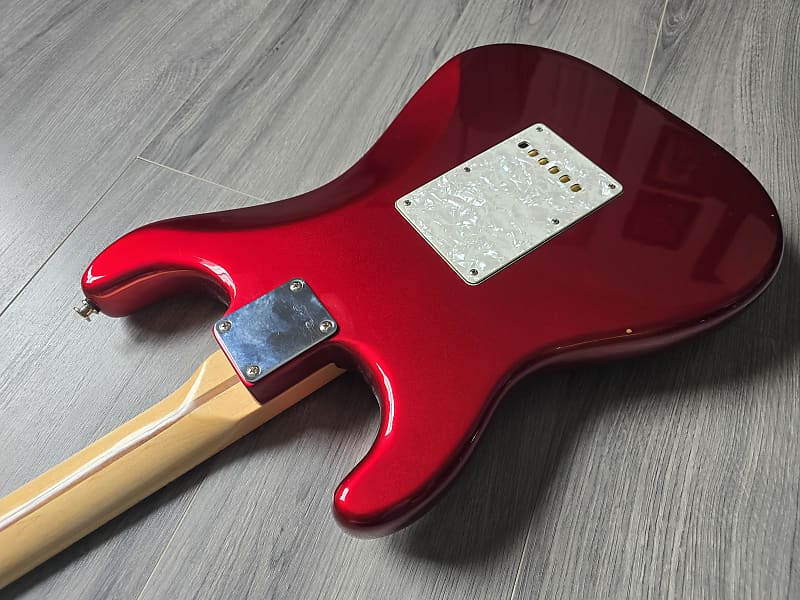 Red electric guitar with a beige neck on a gray wooden surface