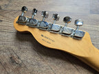 Guitar tuning pegs on a wooden headstock with visible brand name.
