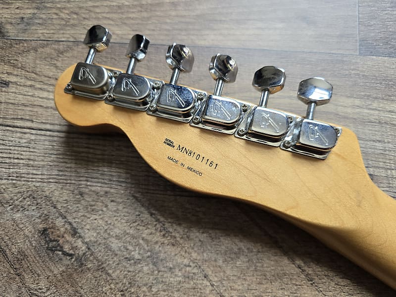 Guitar tuning pegs on a wooden headstock with visible brand name.