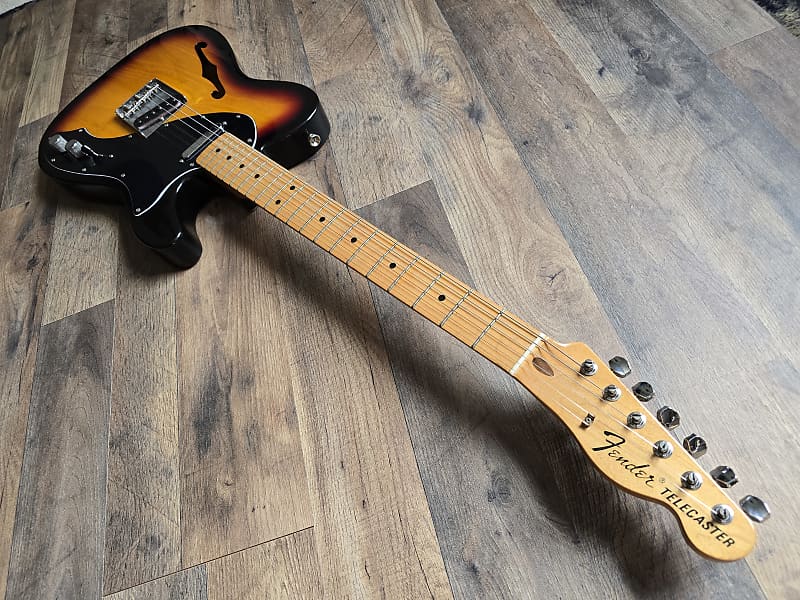 Fender electric guitar displaying neck length and fretboard on a wooden floor