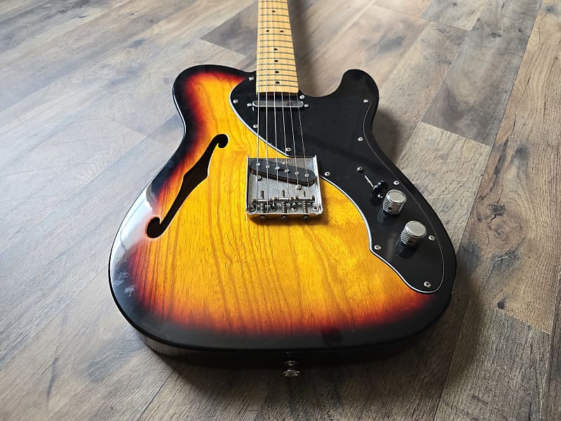 Electric guitar with sunburst finish on a wooden floor