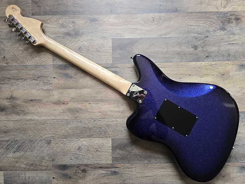 Blue electric guitar body with a maple neck on a wooden floor