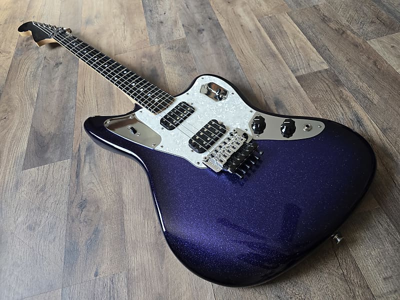 Blue and black electric guitar with a sparkle finish on a wooden floor