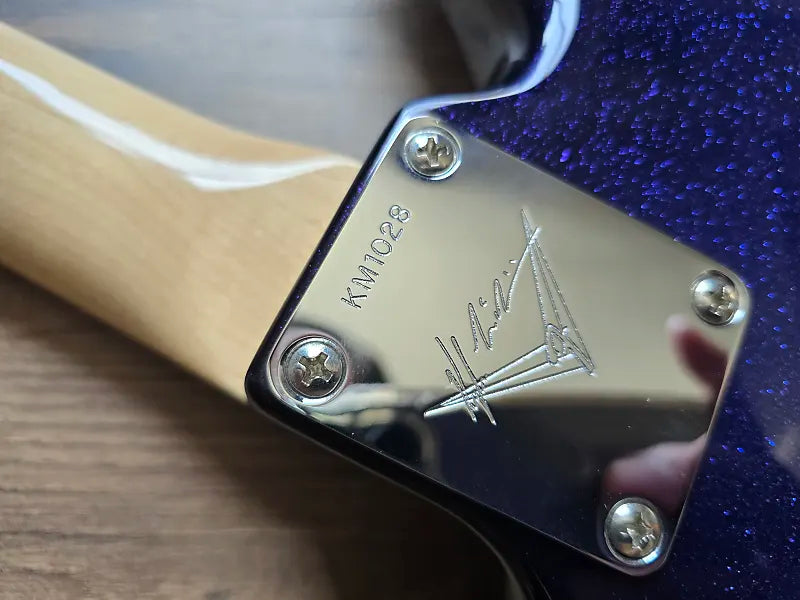 Close-up of a guitar with masterbuilder branding on a wooden surface