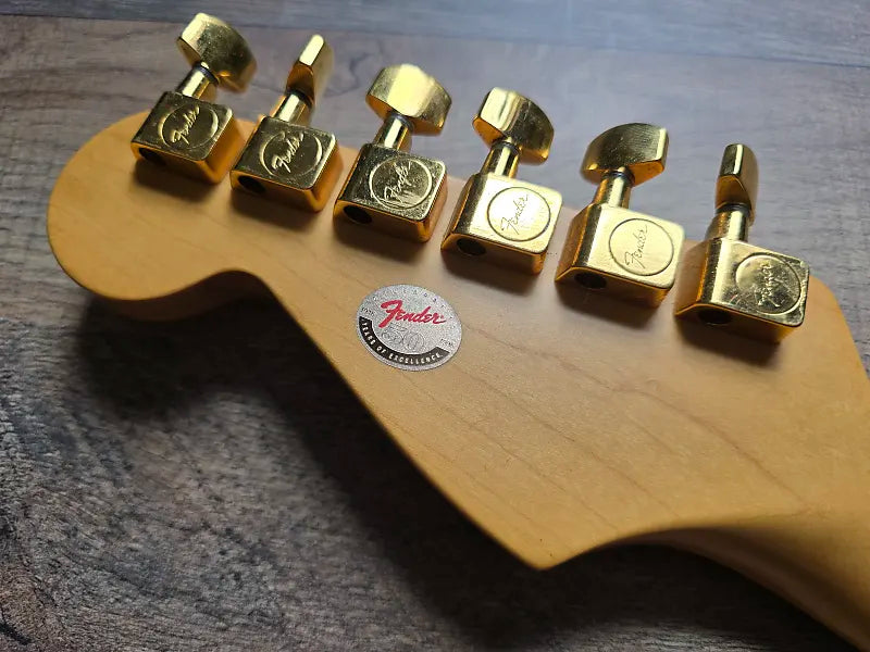 Gold guitar tuners on a wooden guitar body with Fender logo.