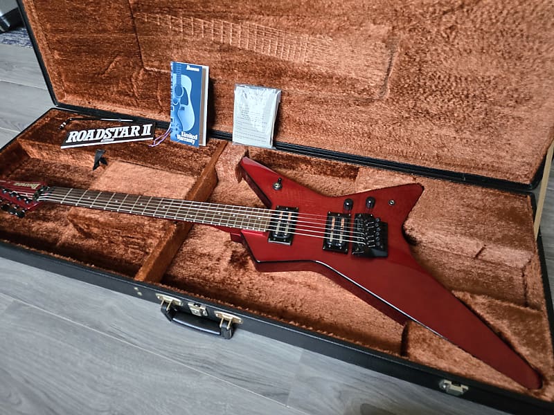 Red Ibanez electric guitar in an open brown case with Roadstar II branding.