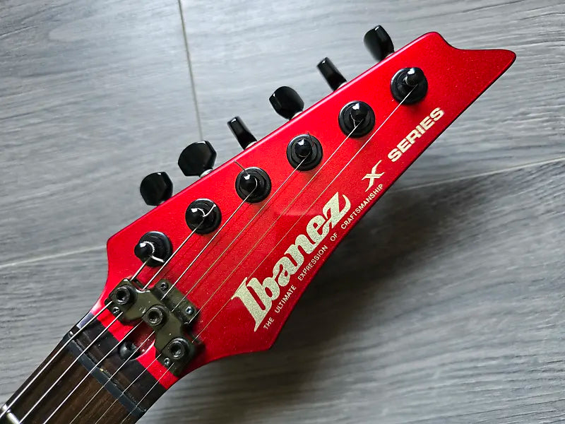 Red Ibanez guitar headstock on a wooden surface