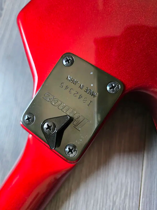 Close-up of a red guitar with a visible Ibanez brand logo and serial number