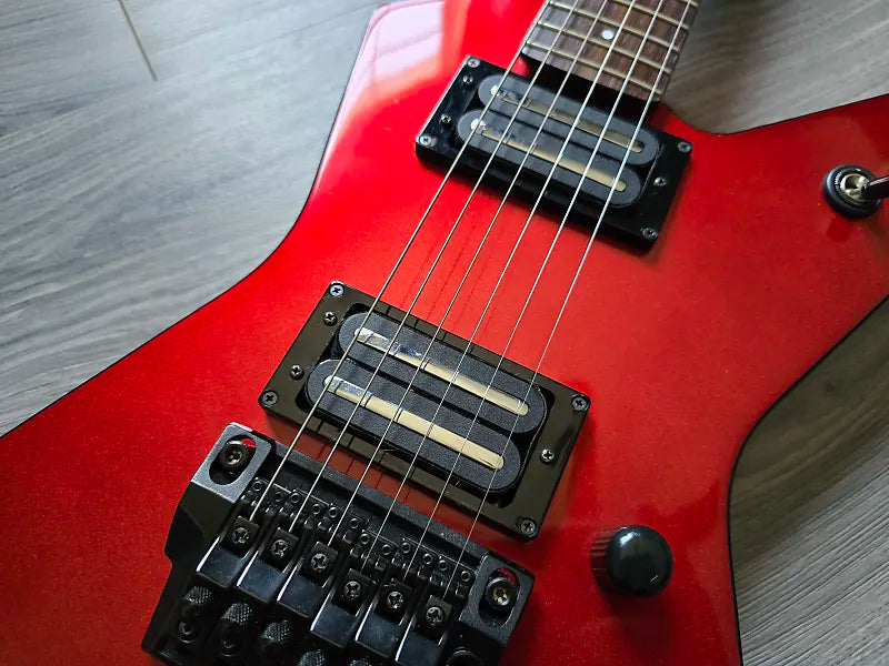 Red electric guitar with black hardware on a wooden surface