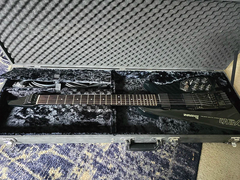 Ibanez electric guitar in a black case on a textured surface