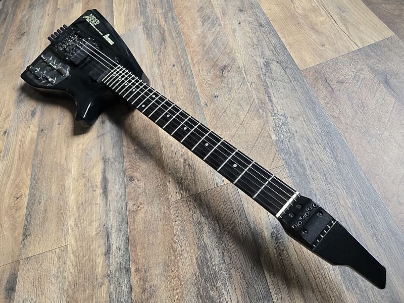Black Ibanez guitar with an ebony fretboard on a wooden floor