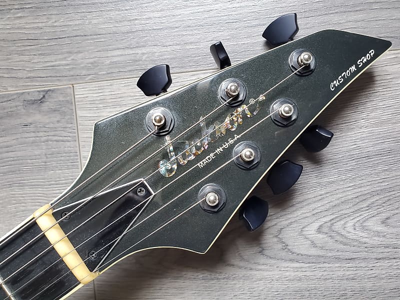 Guitar headstock with 'Jackson Custom Shop' branding on a wooden surface