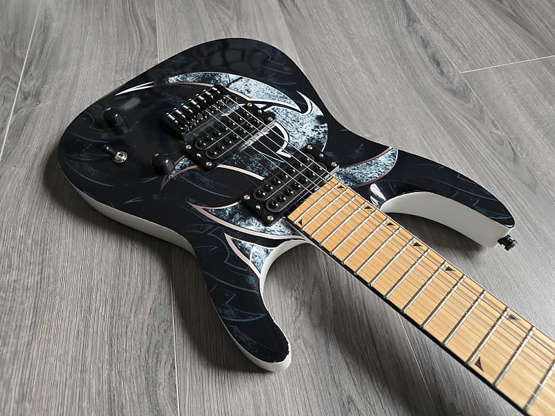 Black electric guitar with white design and maple fretboard