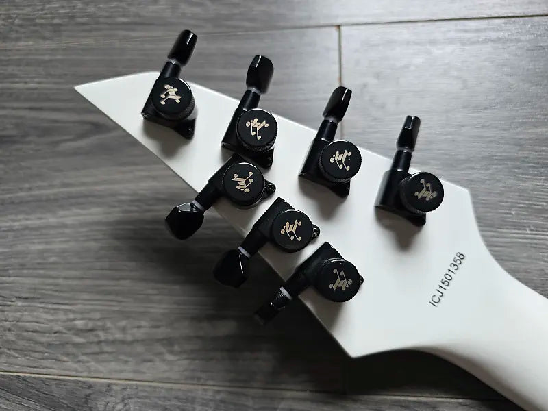 white back of guitar headstock with black tuning pegs and serial number