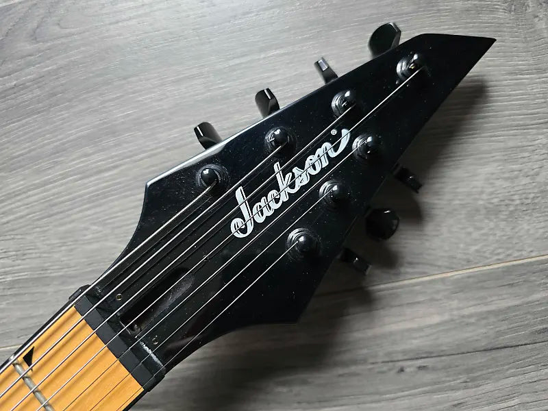 Black Jackson guitar headstock on a wooden surface