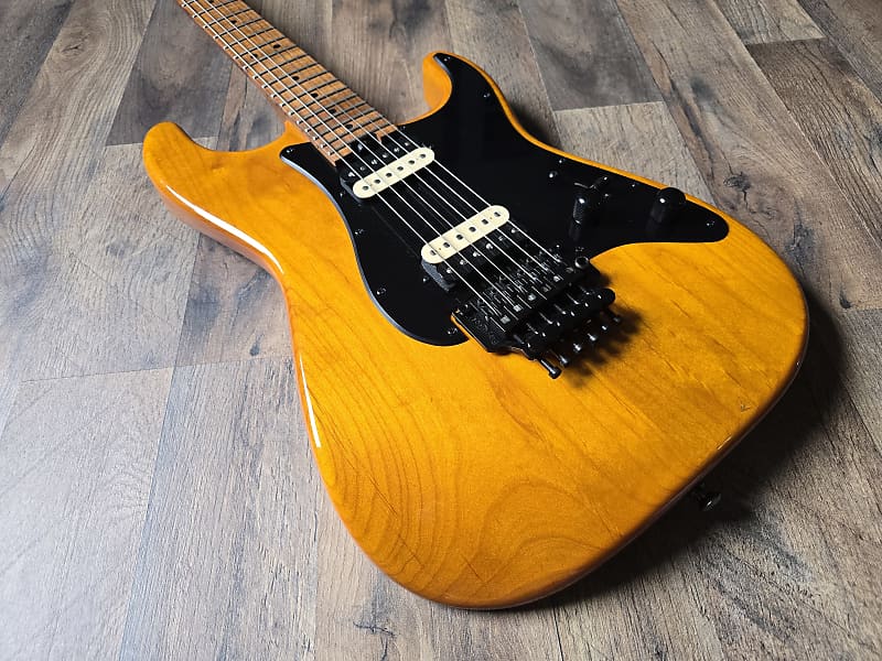 Electric guitar with an orange alder body on a wooden surface