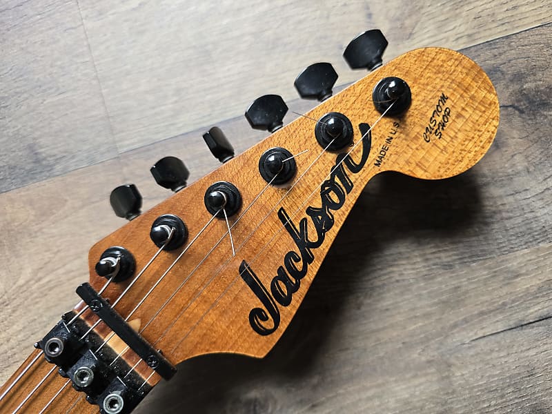 Close-up of a Jackson guitar headstock on a wooden surface