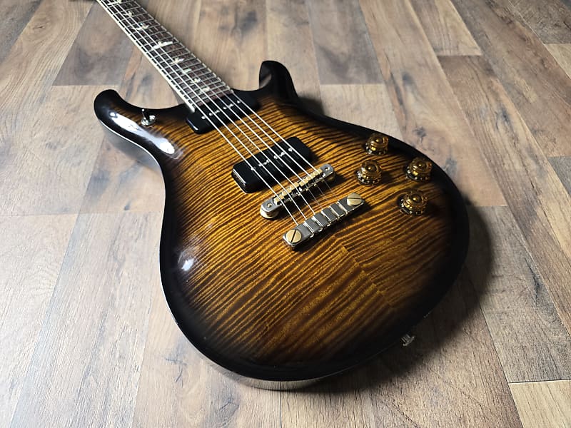 Electric guitar with a yellow flamed maple top on a wooden floor