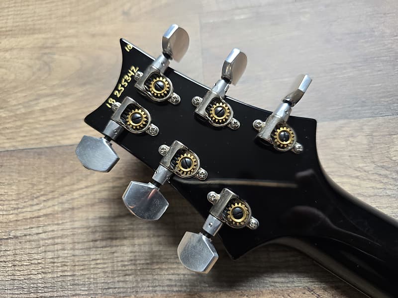 Black guitar headstock with tuning pegs and serial number
