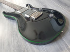 Black electric guitar with gloss finish and green accent on a wooden floor