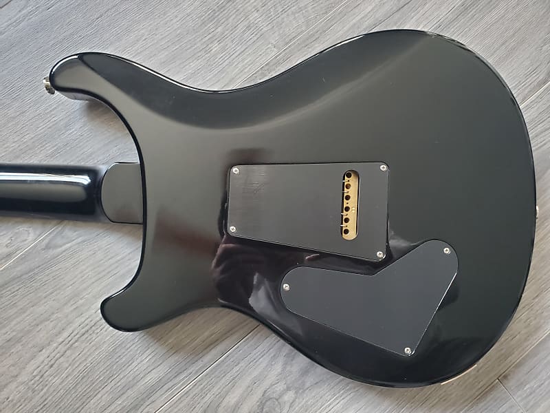 Black electric guitar body on a wooden surface