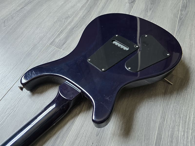 Glossy blue guitar body on a light wooden floor