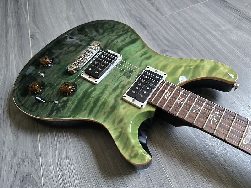 Green electric guitar on a wooden floor