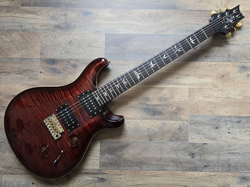Glossy red and black electric guitar on a wooden surface