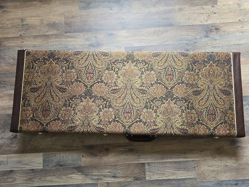 Vintage paisley patterned guitar case lying on a wooden surface