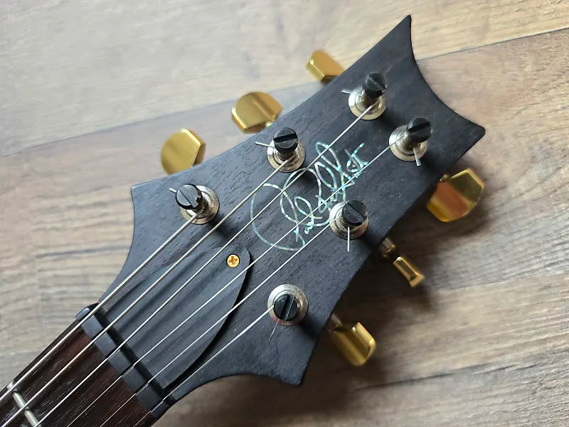 Black guitar headstock with gold tuning pegs and 'Paul Reed Smith' branding