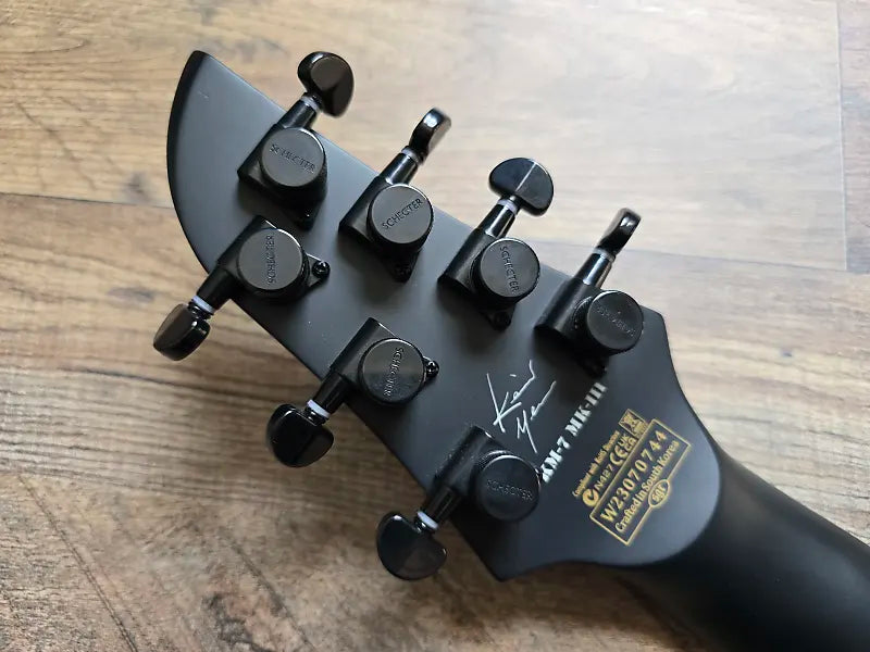 Guitar headstock with tuning pegs on a wooden surface