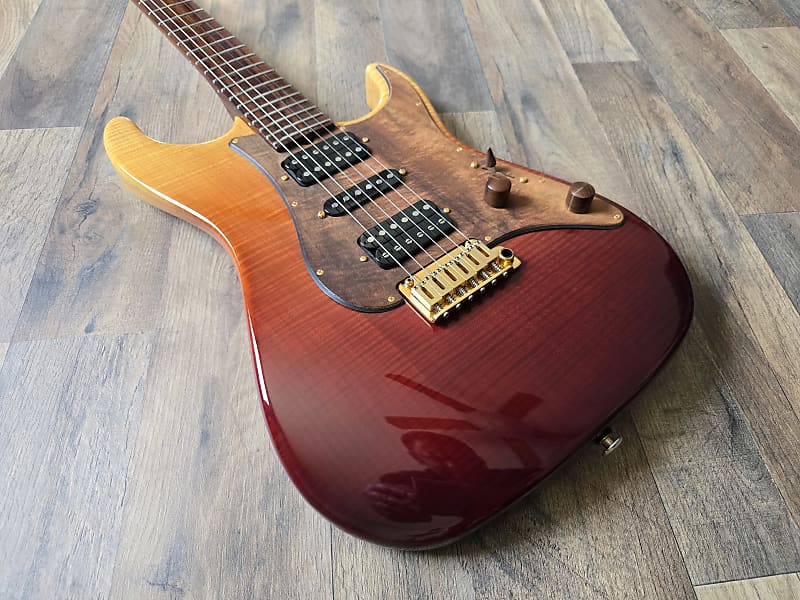 Electric guitar with a red and orange sunburst finish on a wooden floor