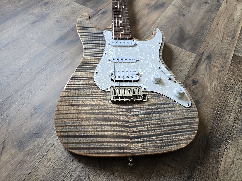 Striped electric guitar with a wood finish on a wooden floor