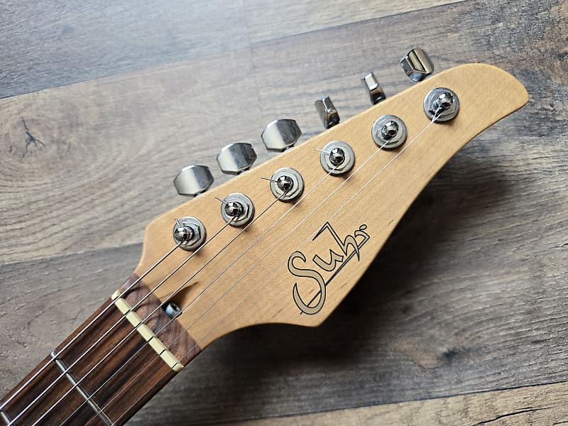 Guitar headstock with 'Suhr' branding on a wooden surface