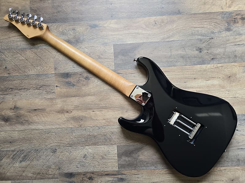 Black electric guitar with a blonde neck on a wooden surface