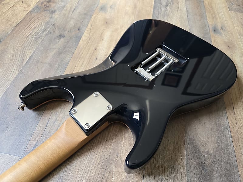 Black electric guitar body on a wooden surface