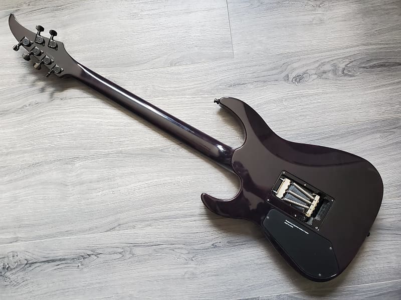 Dark crimson electric guitar face down on a gray wooden surface.
